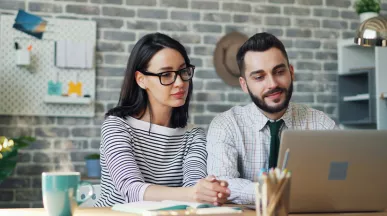 Foto mostra um chefe trabalhando uma pessoa de sua equipe