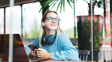 Foto mostra uma pessoa trabalhando em um notebook em uma sala ampla