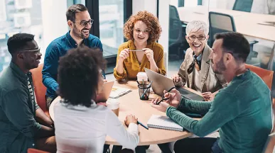 time conversando em torno de uma mesa dentro de escritorio.