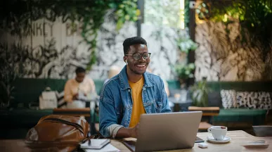 homem sorrindo enquanto usa o notebook.