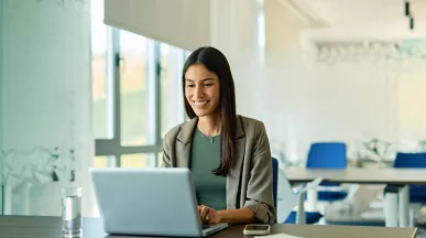 mulher sorrindo enquanto usa o computador no trabalho.