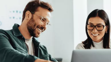 Homem e mulher em um ambiente corporativo, sorrindo 