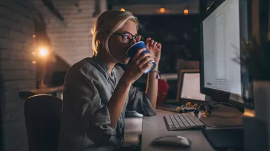 pessoa tomando chá enquanto trabalha à noite.