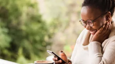 mulher negra sorrindo olhando para o celular