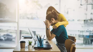 uma mulher oferecendo apoio para outra, que está preocupada com o trabalho.