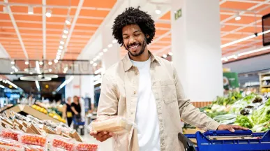 Foto mostra um homem comprando alimentos frescos no supermercado com seu Pluxee Alimentação
