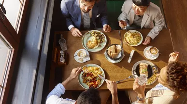 visão aérea time almoçando junto em mesa.