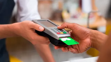 Foto mostra uma pessoa pagando sua conta com um cartão Pluxee