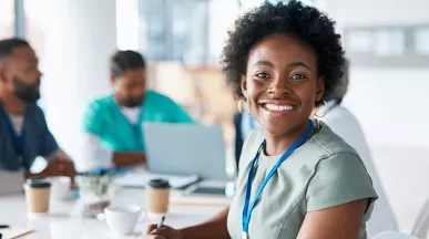 profissional da saúde sorrindo para a câmera rodeada por colegas.