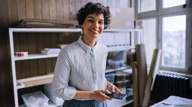 mulher sorrindo em frente a seu empreendimento.