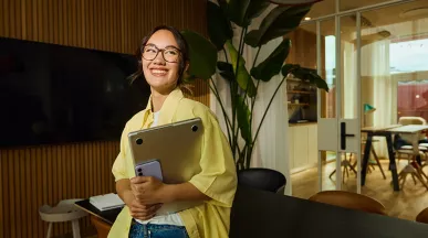 mulher sorrindo enquanto segura notebook.