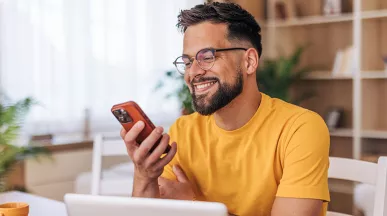 homem sorrindo para algo no celular.