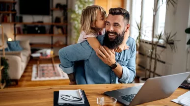 Foto de um homem brincando com sua filha durante um dia de home office