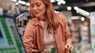 A imagem mostra uma mulher ruiva no mercado, fazendo compras