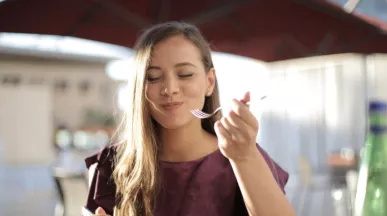mulher sorrindo com um garfo na mão 