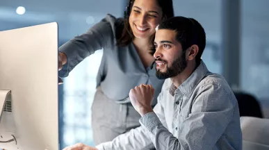 mulher mostrando algo a homem em tela de computador.