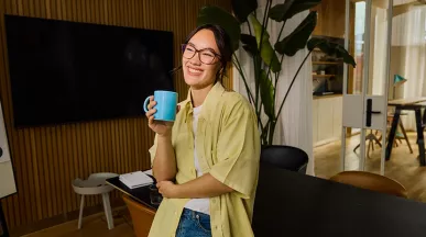 mulher sorrindo enquanto bebe algo em caneca.