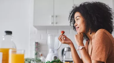 mulher olhando pela janela com um morango na mão 