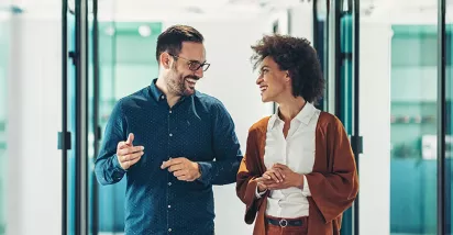 duas pessoas conversando em corredor de escritório.