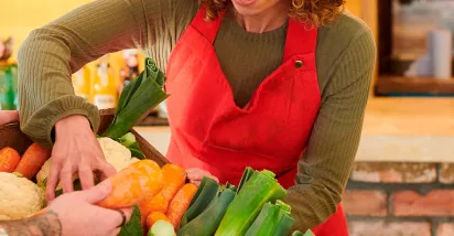 foto mostra duas pessoas mexendo em uma cesta de legumes frescos