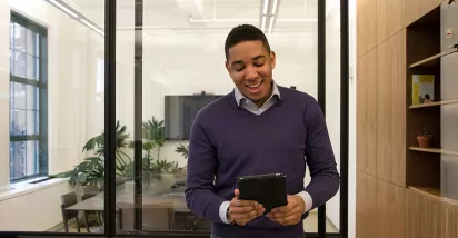 Foto mostra uma pessoa no escritório trabalhando no seu tablet