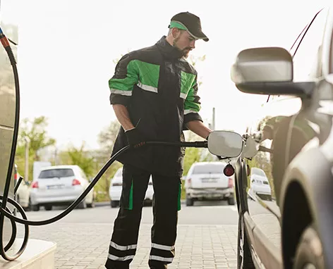 Foto mostra frentista de posto abastecendo um veículo