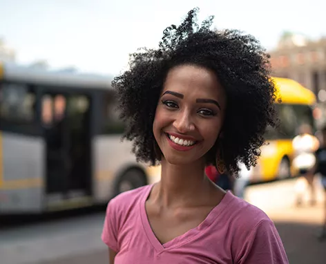 Mulher sorri com um ponto de ônibus ao fundo