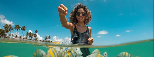 Mulher aproveita férias na praia com seguro viagem