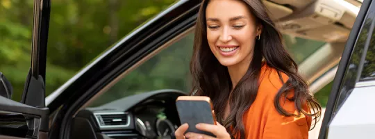 A foto mostra uma mulher sentada no seu carro