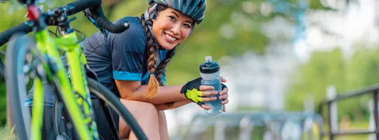 A foto mostra uma mulher sentada em sua bicicleta 