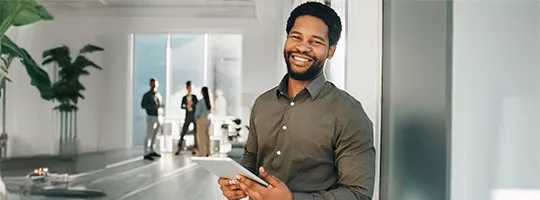 Foto mostra jovem trabalhador no escritório com um tablet na mão