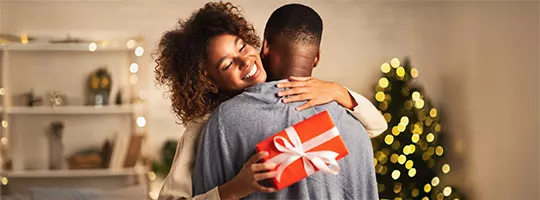 Foto mostra uma mulher recebendo um presente comprado com o cartão Pluxee