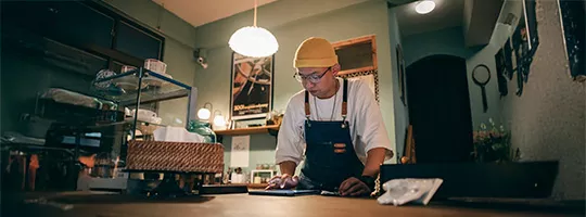 Foto mostra o dono de um pequeno negócio trabalhando à noite