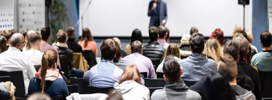 Público assistindo a uma palestra em auditório.