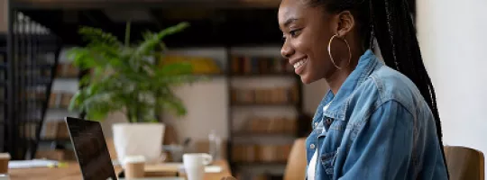 Pessoa usando notebook em mesa de escritório com planta ao lado