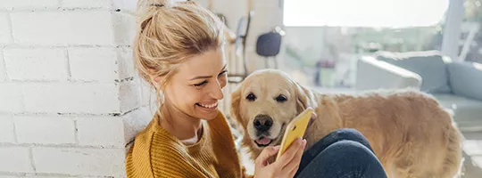 Mulher vê novidades no celular com seu cachorro de estimação 