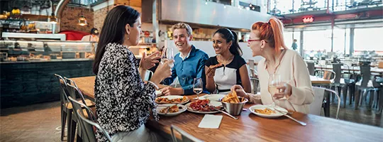  Foto mostra grupo de colegas de trabalho comendo no restaurante