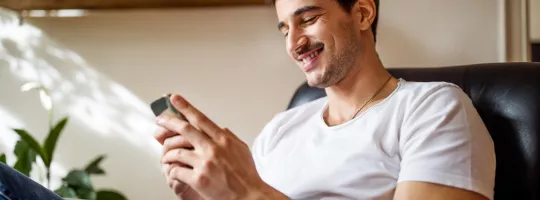 Pessoa utilizando smartphone em ambiente residencial, representando autonomia e qualidade de vida abordadas na pesquisa Pluxee + Ipsos 2026