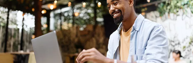 Homem trabalha no seu computador e sorri