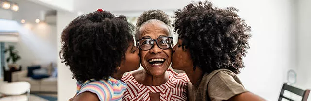 Avó sorri ao receber o beijo de dois netos