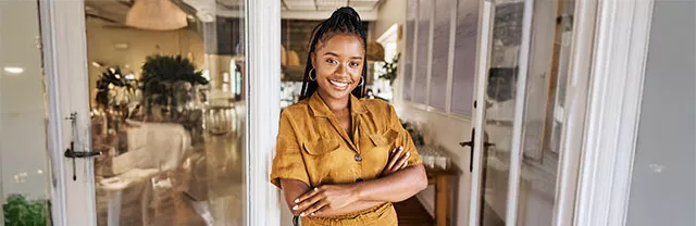 Foto mostra jovem empreendedora na frente do seu escritório
