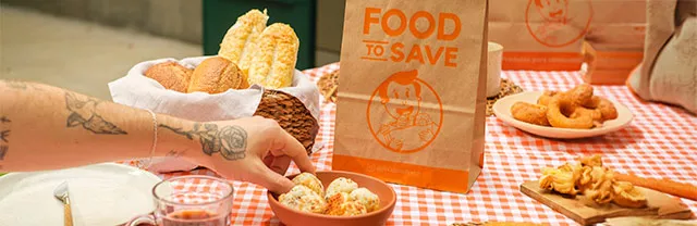 Foto mostra uma mesa de café posta e uma sacola do Food to Save