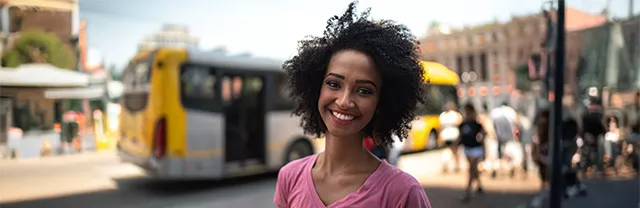 Foto mostra uma jovem profissional com um ônibus ao fundo