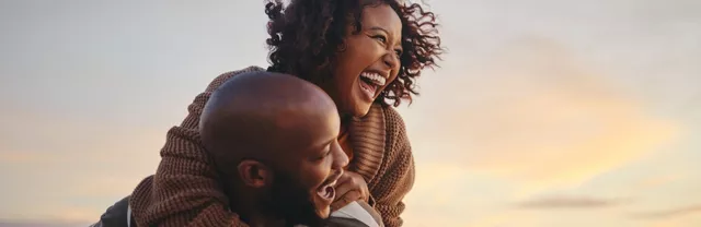 uas pessoas se abraçam ao pôr do sol, representando apoio e doação.