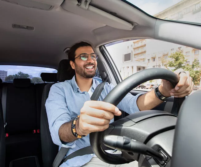 Homem dirige o carro em direção ao trabalho. O abastecimento foi feito com vale-combustível Pluxee.