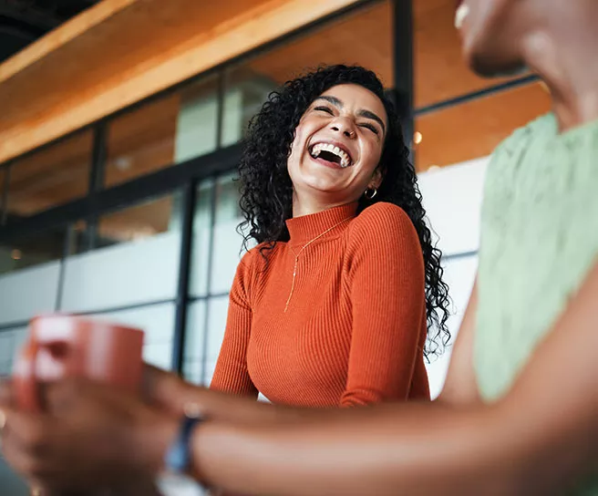 Colegas de trabalho conversam animadas na sala de reunião