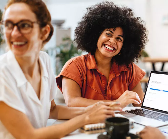 Foto mostra duas colegas de trabalho durante uma conversa animada