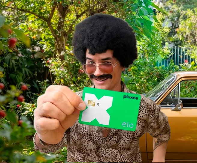 Homem mostra o cartão Pluxee Multibenefícios com bandeira Elo