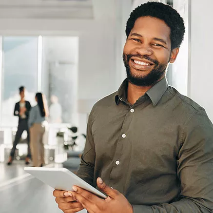 Empreendedor usa seu tablet e sorri para a câmera