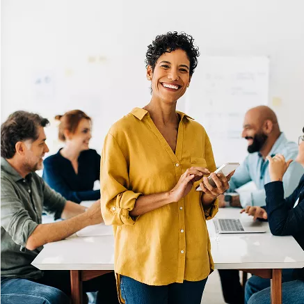 Grupo de pessoas em reunião com laptops e quadro branco em ambiente de trabalho colaborativo